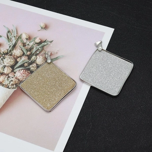 Detail of square glitter pendants with gold and silver finishes and metal edging