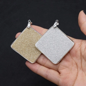 Detail showing square shell pendants with frosted glitter surface in gold and silver