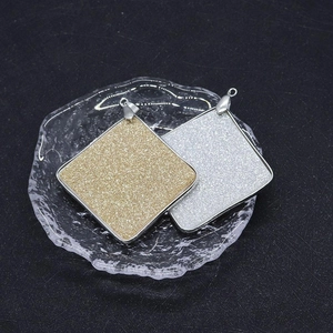 Macro view of square natural shell pendants with gold and silver matte glitter textures