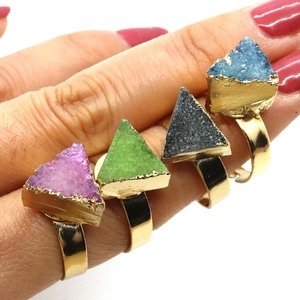 Detalle de cuatro anillos de cristal druzy triangular de colores en banda dorada