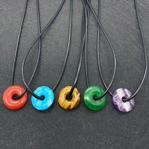 Five assorted natural stone donut pendants including amethyst and tiger eye on black cords