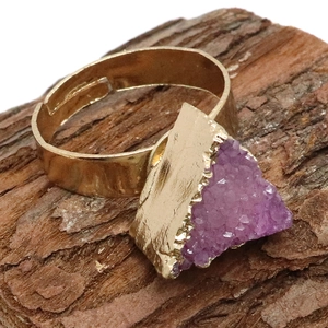 Detalle de anillo de cristal druzy púrpura triangular con banda dorada ajustable en madera
