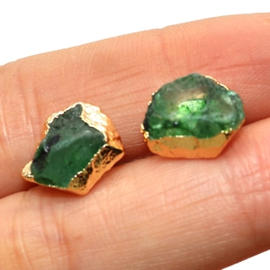 Detailed macro view of raw green stone earrings with irregular gold-plated edges