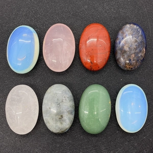 Detailed top view of 8 polished oval gemstone cabochons on a black textured background