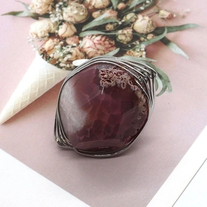 Detailed wire-wrapped silver finish on a faceted purple agate stone with white patterns