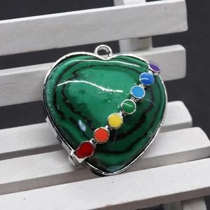 Détail macro d'un pendentif malachite en cœur avec sept pierres de chakra sur bande argent
