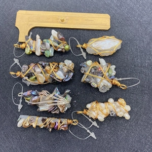 Macro view of handmade wire-wrapped natural pearl and crystal pendants with brass caliper