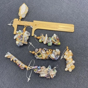 Macro view of handmade wire-wrapped natural stone pendants with brass caliper for scale