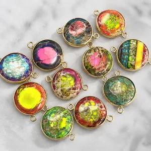 Macro detail of round multi-color natural emperor stone pendants with gold metal frames