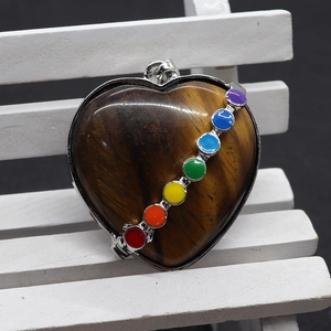 Pendentif cœur en œil de tigre avec sept pierres de chakra sur un petit banc