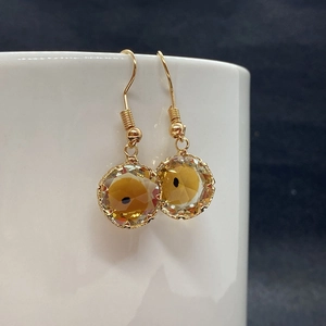 Macro detail of amber evil eye crystal pendant on gold wire wrapped ear hook accessory