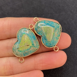 Macro detail of heart-shaped turquoise stone connector with gold plating and double loops