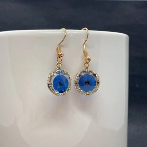 Bohemian gold plated evil eye drop earrings with faceted blue crystal set on white cup