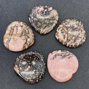 Détail macro de pierres de rhodonite en forme de cœur aux textures polies roses et noires