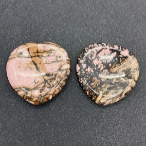 Vue détaillée de deux pierres de massage en rhodonite polies en forme de cœur naturel