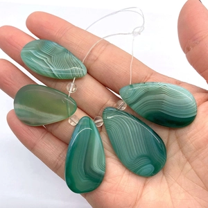 Macro shot of green striped agate teardrop beads for DIY jewelry making held in hand