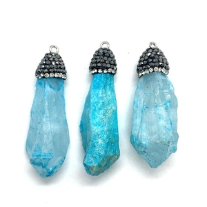 Détail de trois pendentifs en cristal bleu naturel avec des capuchons en métal sertis