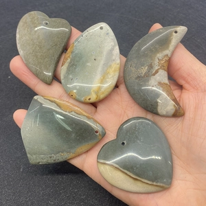 Polished grey and beige natural agate stone pendants in heart and moon shapes held in hand