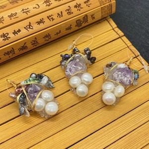 Handmade amethyst and pearl grape-shaped pendant with gold wire wrapping on bamboo mat
