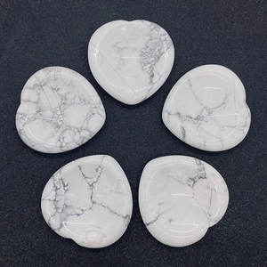 Détail macro de cinq pierres de howlite blanche en forme de cœur avec veines naturelles