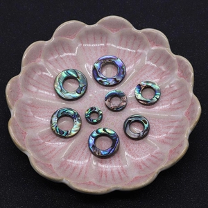 Macro di perle ad anello in conchiglia di abalone su un piatto di ceramica rosa
