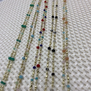 Detailed macro view of gold beaded chain with mixed colorful faceted crystal gemstones
