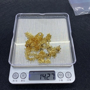 Dettaglio di una catena a foglie dorata da 7 mm pesata su una bilancia digitale