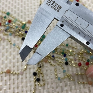 Detail view of 4mm multi-color natural stone beads on a gold copper chain with calipers