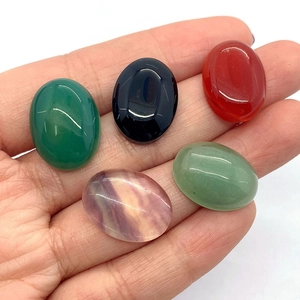 Polished oval natural gemstones in hand including aventurine and onyx for DIY jewelry