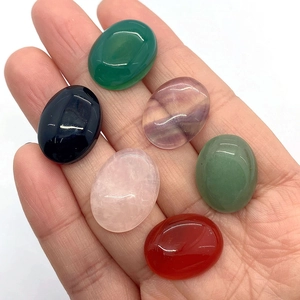 Macro shot of six oval natural gemstone cabochons held in palm for size reference