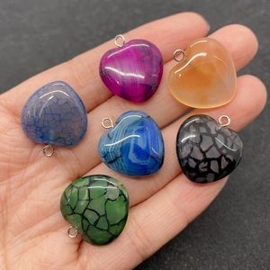 Selection of heart-shaped striped agate stone pendants held in hand for size comparison