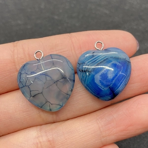 Macro shot of 20mm striped agate heart pendants held in hand for DIY jewelry making