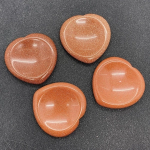 Macro detail of four heart-shaped goldstone worry stones with polished concave surface