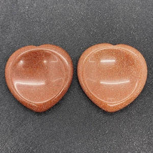 Macro detail of heart-shaped goldstone thumb stones with sparkling red-brown finish