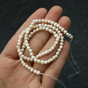 Dettaglio macro di perle d'acqua dolce barocche bianche naturali tenute in mano