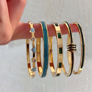 Lot de cinq bracelets en acier titane doré avec cœurs en émail et cristaux incrustés