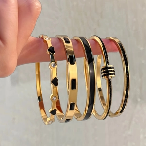Cinq bracelets assortis en acier titane doré avec cœurs noirs et détails en émail