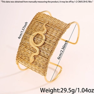 Detailed close-up of woven gold cuff bracelet with embossed snake and heart motif