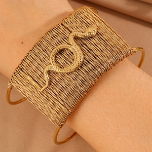 Macro detail of golden woven metal bracelet featuring an intricate engraved snake design