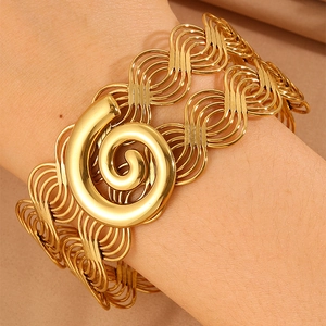 Detail of wide gold braided cuff bracelet with spiral ornament on champagne silk