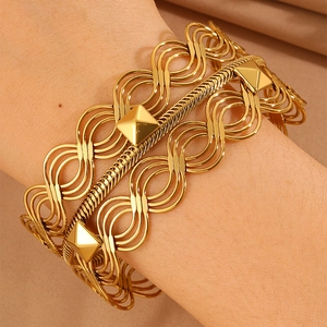 Macro shot of gold wide woven bangle with geometric pyramid studs and wave hollow design