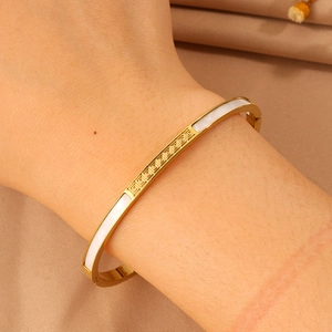 Close-up of golden stainless steel bracelet with Greek meander pattern and shell inlay