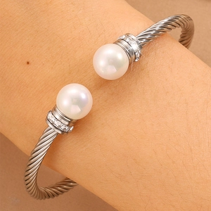 Gros plan détaillé d'un bracelet câble avec perles blanches et anneaux diamants sur bras