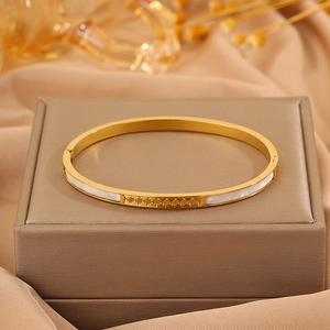 Detail of golden stainless steel bracelet with shell inlay and Greek key design