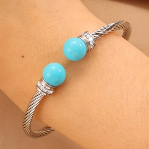 Gros plan sur un jonc torsadé argenté avec perles turquoise et accents de zircon