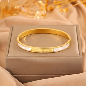 Detailed macro view of gold-plated stainless steel bracelet with white shell inlay and Greek Key