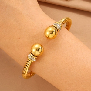 Détail d'un bracelet jonc torsadé doré avec zircons scintillants porté au poignet