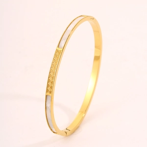 Close-up of golden stainless steel bangle with mother of pearl and Greek key pattern
