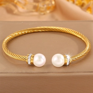 Détail d'un bracelet torsadé plaqué or 18 carats avec perles blanches et strass brillants