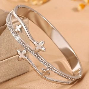 Détail d'un bracelet vague argenté serti de diamants et orné de motifs trèfle à quatre feuilles